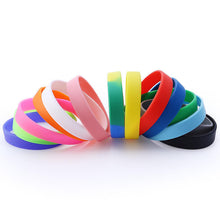 A set of colorful silicone wristbands arranged in a fan shape on a clean white background. The wristbands come in multiple solid colors including pink, orange, white, green, blue, yellow, red, and black, as well as a blue and yellow gradient pair.