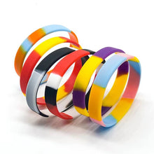 A set of silicone bangles with multicolor tie-dye patterns, including shades of yellow, blue, red, purple, orange, black, and white, arranged on a clean white background.