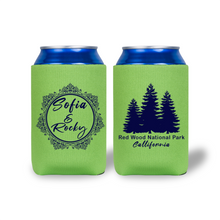 Two green can coolers with blue tops, one featuring a decorative name design and the other with a forest graphic.