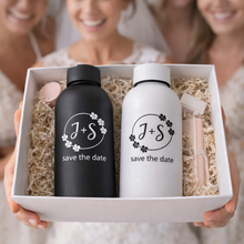 Two water bottles with 'J+S save the date' text in a box held by people.